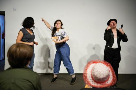 Dwie prowadzące i aktor grający Charliego Chaplina stoją przed publicznością.