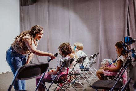 Prowadząca przystawia dziewczynce mikrofon.