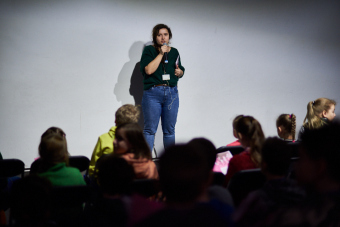 Klub filmowy dla najmłodszych w ramach Magicznej Latarni. Na zdjęciu widzimy stojącą prowadzącą, która przemawia do dzieci.