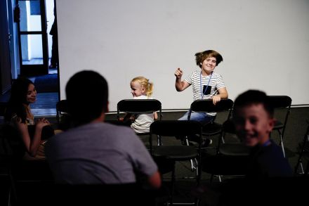 Dzieci siedzące w pierwszym rzędzie widowni odwracają się do tyłu.