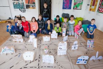 Zdjęcie ukazuje wszystkich uczestników warsztatu wraz z makietą miasta]