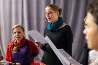 Zbliżenie na dwie uczestniczki, Jedna stoi, druga siedzi, obydwie śpiewają