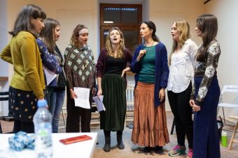 Na zdjęciu widzimy  jak cała grupa razem z prowadzącą śpiewa, stojąc w półkolu.