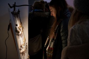 Zdjęcie ukazuje stoisko z zawieszkami na rzemykach, oglądane z zainteresowaniem przez przybyłe na targi  osoby.