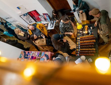 Zdjęcie zrobione z góry. Ludzie chodzą między stoiskami wystawców i oglądają różne produkty.