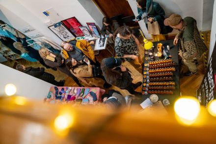 Zdjęcie zrobione z góry. Ludzie chodzą między stoiskami wystawców i oglądają różne produkty.