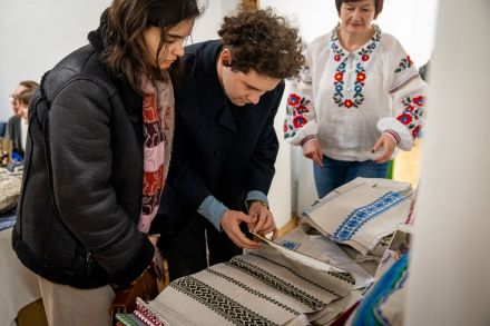 Kobieta i mężczyzna oglądają haftowane obrusy i poszewki.