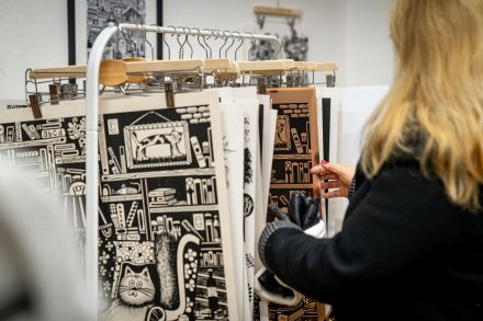 Kobieta ogląda czarno-białe plakaty z kotami.