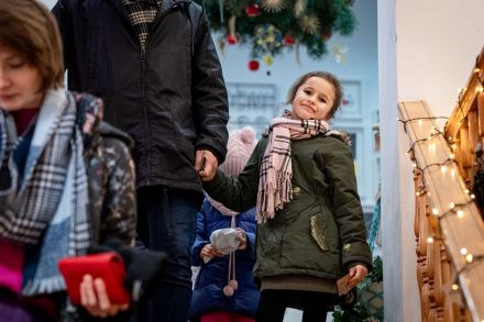 Dziewczynka stoi pod podłaźniczką i uśmiecha się do zdjęcia.