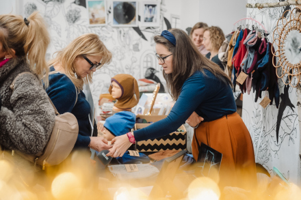 Kobieta prezentuje czapkę klientce. 