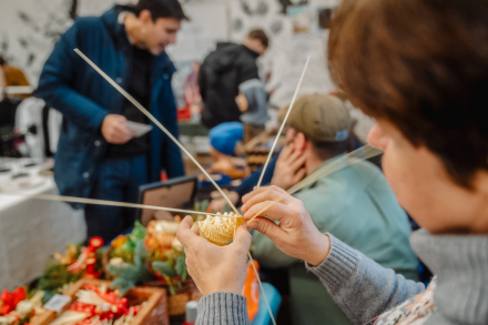 Na stoisku twórczyni robi ze słomy bombkę. 