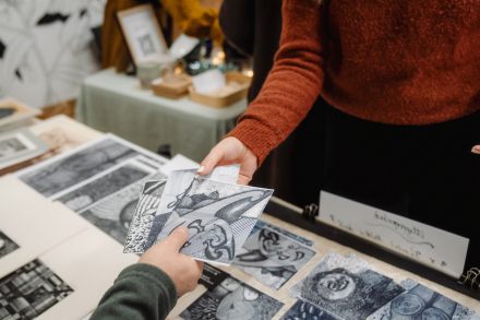 Mężczyzna podaje klientce odbitkę grafiki.