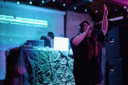 Wokalistka z rękami uniesionymi nad głową.