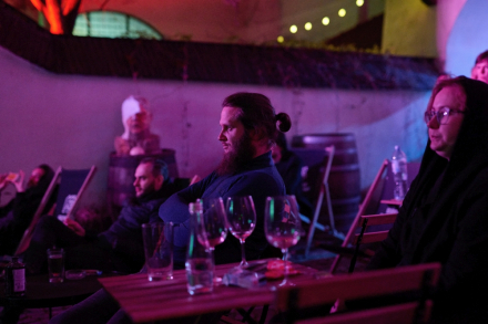 Ludzie siedzą na leżakach i słuchają muzyki.