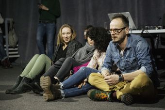 Widzowie Strefy Innych brzmień siedzą na podłodze po turecku na koncercie i słuchają muzyki.