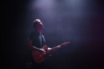 Gitarzysta zespołu Alpha Strategy podczas koncertu. Lekki półmrok.