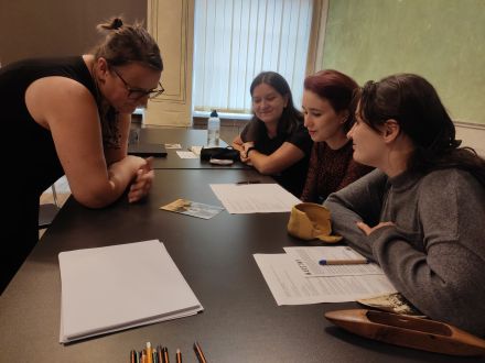 Kobiety przyglądają się staremu zdjęciu kobiety w stroju ludowym.