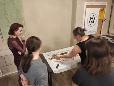 Prowadząca pokazuje i tłumaczy kobietom  przeznaczenie przedmiotów.