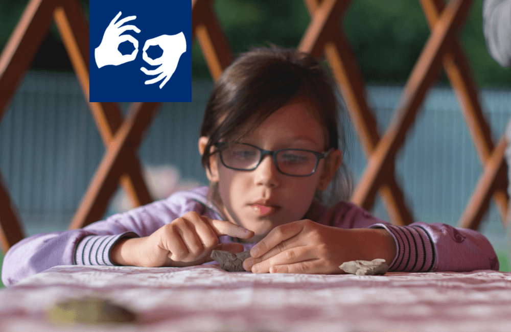 Dziewczynka siedzi przed stołem i wykonuje pracę plastyczną