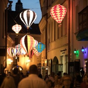 zdjęcie ilustracyjne. Tłum osób podczas Nocy Kultury, ponad głowami podświetlona instalacja artystyczna składająca się z małych kolorowych balonów lotniczych