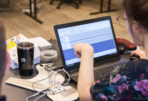 Kobieta pokazująca palcem na wykres fali na dźwiękowej na monitorze