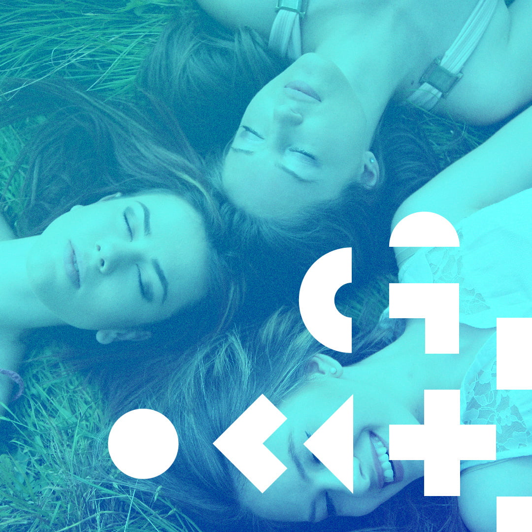 Zdjęcie trzech młodych kobiet leżących na sianie. W dolnej części grafiki znajdują się geometryczne symbole.