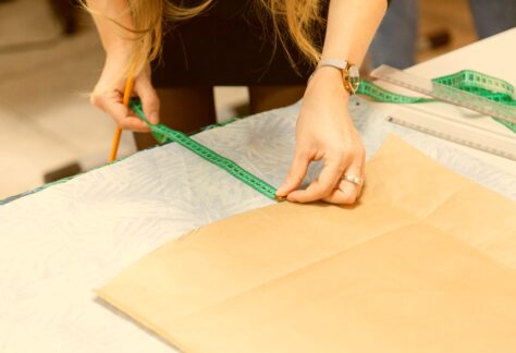 Kobieta mierząca materiał miarką krawiecką