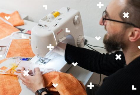 Na zdjęciu widać mężczyznę przy maszynie do szycia. Drobne elementy graficzne przypominające bloki z gry tetris porozrzucane są na całym obrazku.