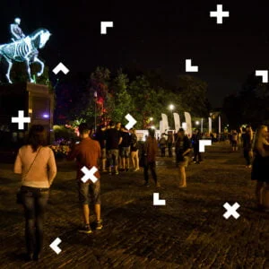 Plac Litewski w Lublinie nocą. Ludzie zgromadzeni wokół pomnika Józefa Piłsudskiego, który jest podświetlony tak, aby widzieć szkielet konia i jeźdźca.