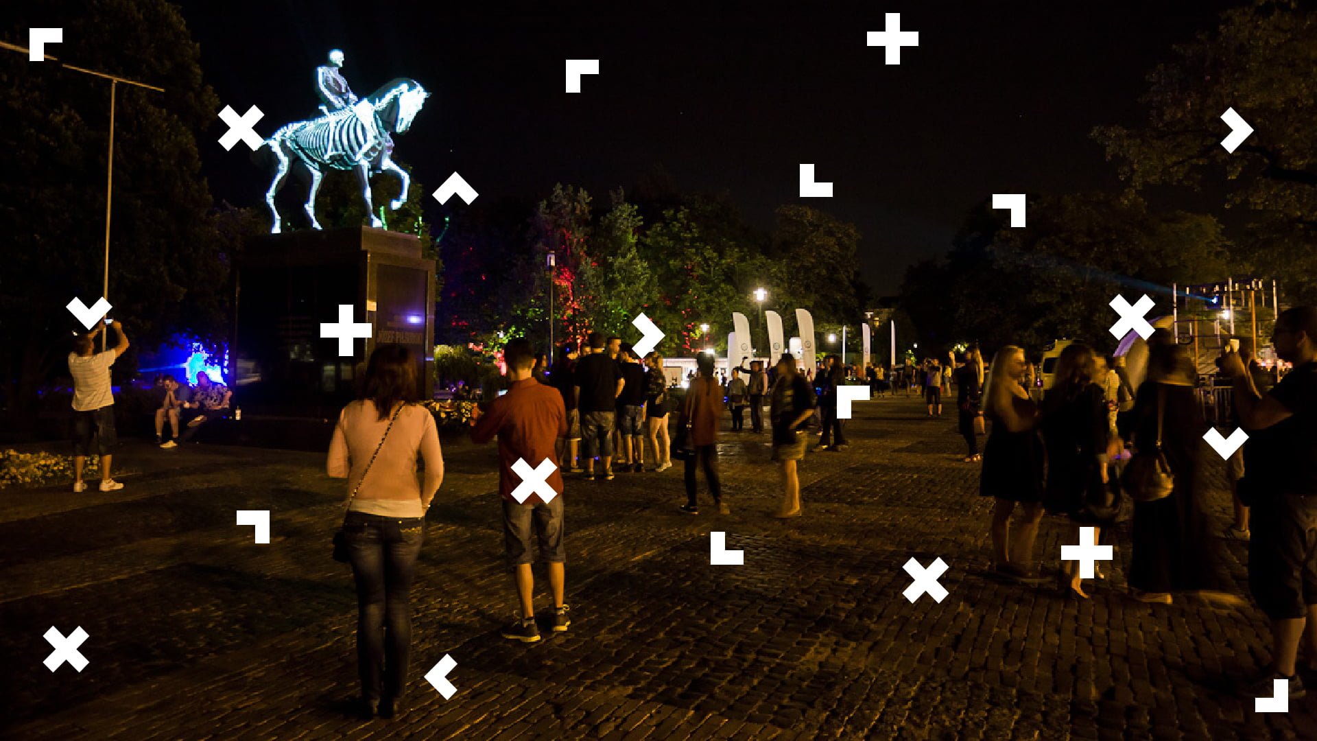 Plac Litewski w Lublinie nocą. Ludzie zgromadzeni wokół pomnika Józefa Piłsudskiego, który jest podświetlony tak, aby widzieć szkielet konia i jeźdźca.