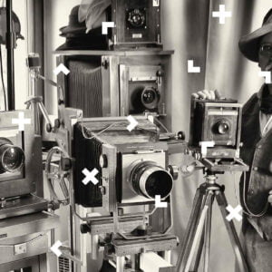 Czarno-biała fotografia Romana Krawczenki, który stoi przy starych aparatach analogowych.