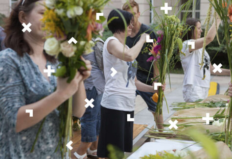 Kobiety stoją przy stole pełnym kwiatów i układają bukiety w stylu boho.