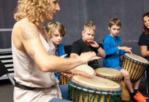 Czwórka dzieci i kobieta grają na bębenkach.