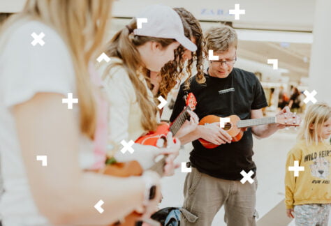 Mężczyzna i dwie dziewczyny uczą się gry na ukulele.