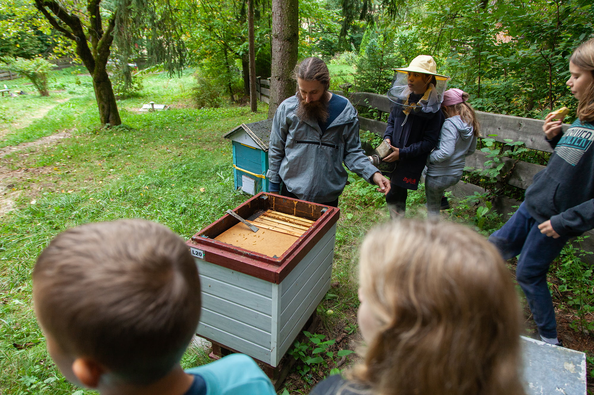 Pszczelarz pokazuje dzieciom środek ula.
