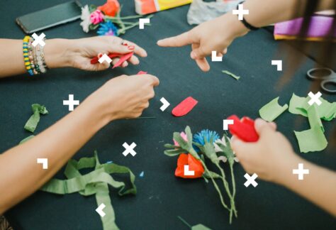 Przy stole kobiety robią bukiety z bibuły.