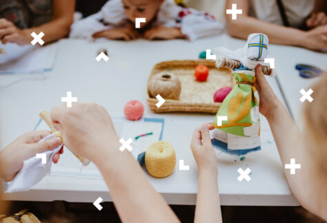 Przy stole dzieci robią lalki motanki.