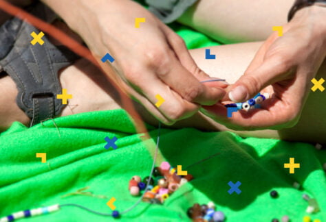 Dłonie kobiety, która robi bransoletkę z koralików.