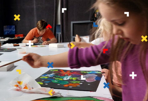 Dziewczynka maluje na czarnej kartce farbami.