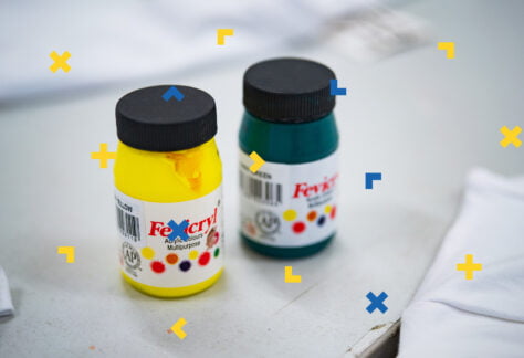 Na stoliku leżą pojemniki z farbami i tkanina.