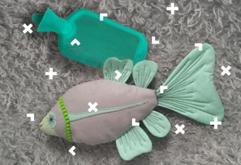 Na dywanie leż pluszowa ryba i wkład do termoforu.