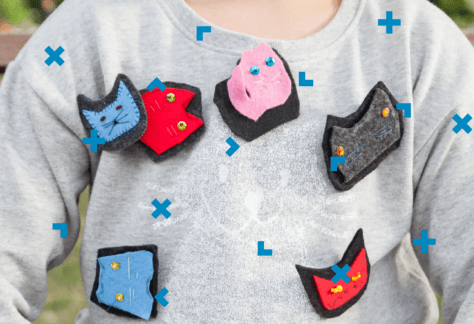 Pierś dziecka, które ma na koszulce przypięte broszki.