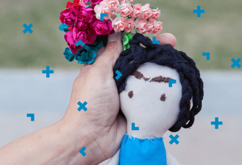 Dłoń kobiety, która trzyma lalkę motankę.