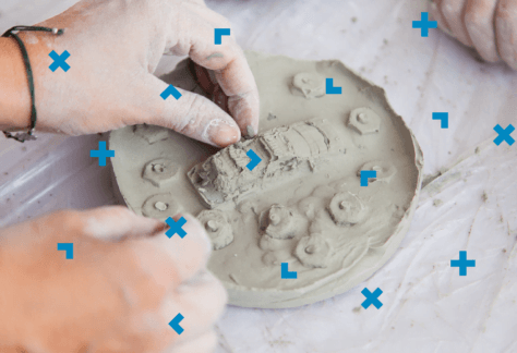 Dłonie kobiety, która rzeźbi w masie plastycznej samochód.