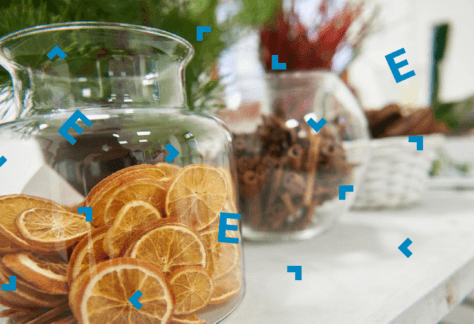 Na stole słoiki z suszonymi pomarańczami i cynamonem.