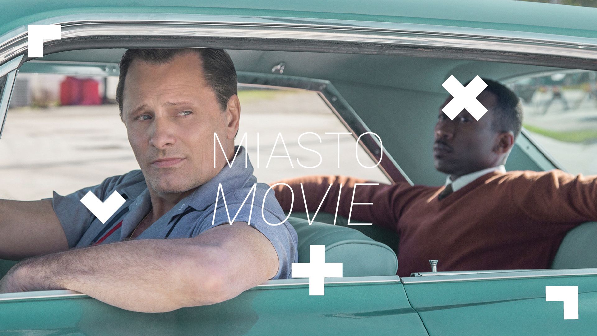 Kadr z Filmu "Green Book". Dwóch mężczyzn siedzi w zielonym samochodzie. Na zdjęciu widnieje biały napis "Miasto Movie"