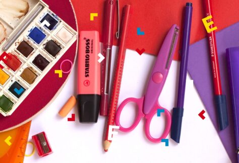 Na stole leżą nożyczki, ołówki, flamastry i farby do malowania.