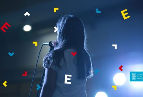 Dziewczynka stoi tyłem przy mikrofonie.