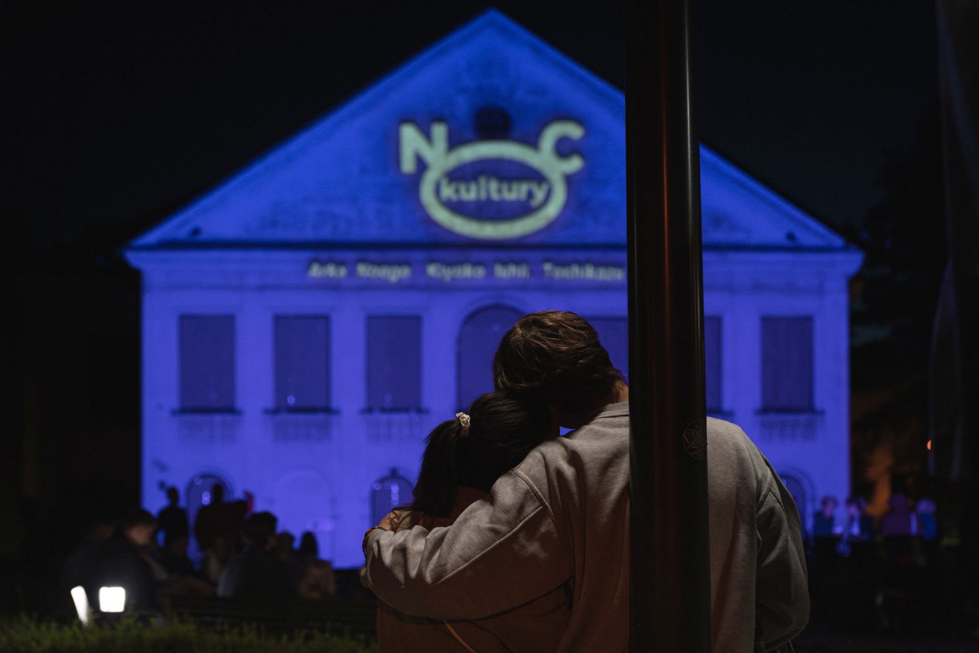 Kobieta i mężczyzna stoją przytuleni i oglądają mapping podczas Nocy Kultury.