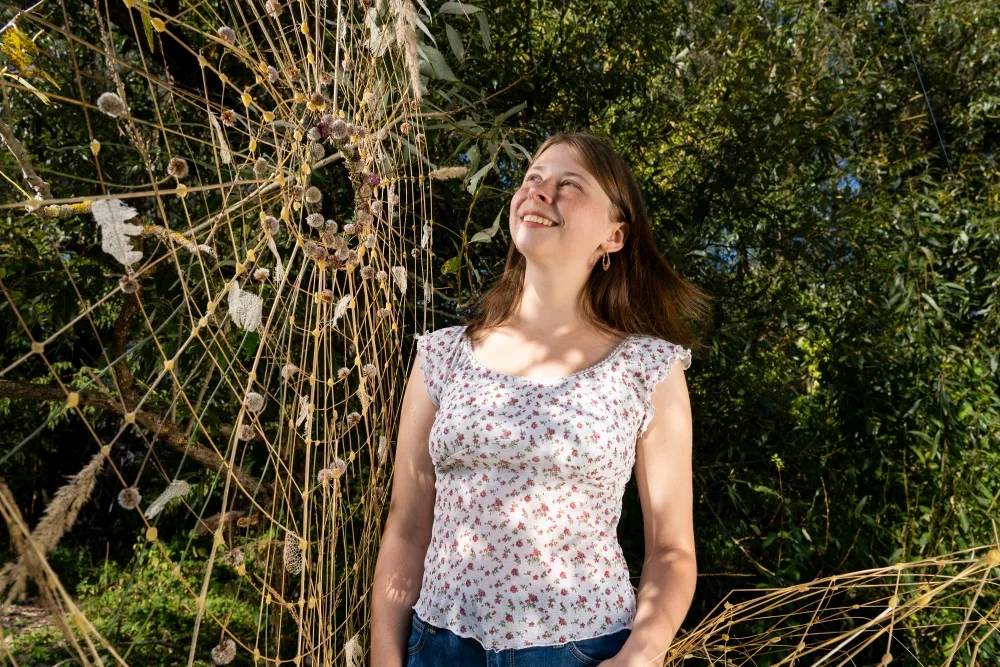 Dziewczyna przygląda się pajęczynie z wikliny, którą sama zrobiła.